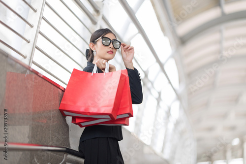 Attractive and Exusive Business Woman Wearing Modern Sunglasses With Lot of Red Shopping Bags. Happy After Working Hard.