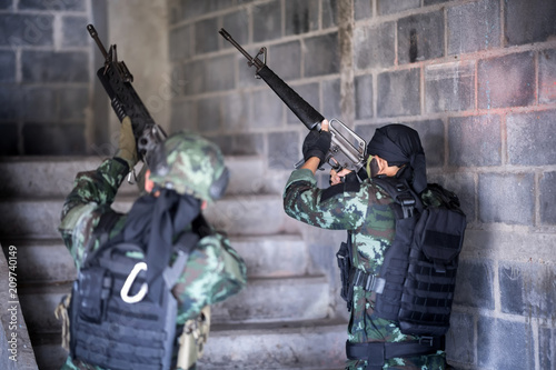 Asian army soldier with rifle and machine gun moving patrol around building. selective focus at gun of  human right side
