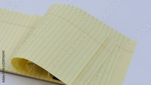 Panning Lined yellow note pad in wind