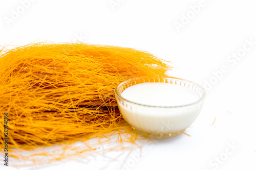 Close up of Raw vermicelli or sevee or seviyan or seviyaan isolated on white with a bowl of milk used to make kheer. photo