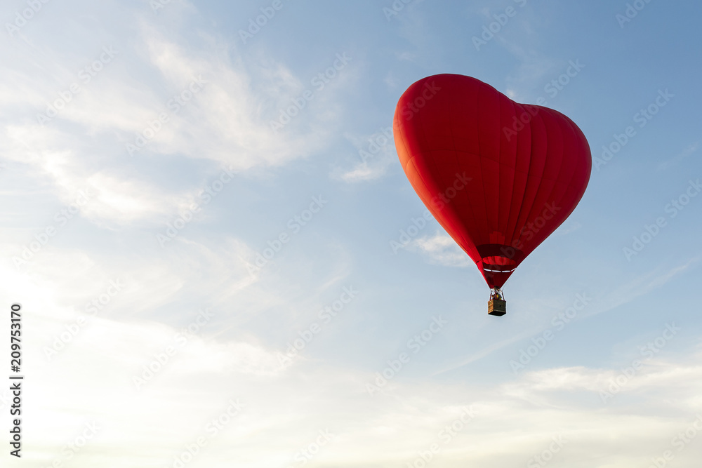Red hot air balloon in the shape of a heart fly in sky. Love, honeymoon and romantic travel concept Red hot air balloon in the shape of a heart fly in sky. Love, honeymoon and romantic travel concept