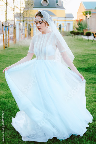 Charming young bride in white dress and veil walking to the church