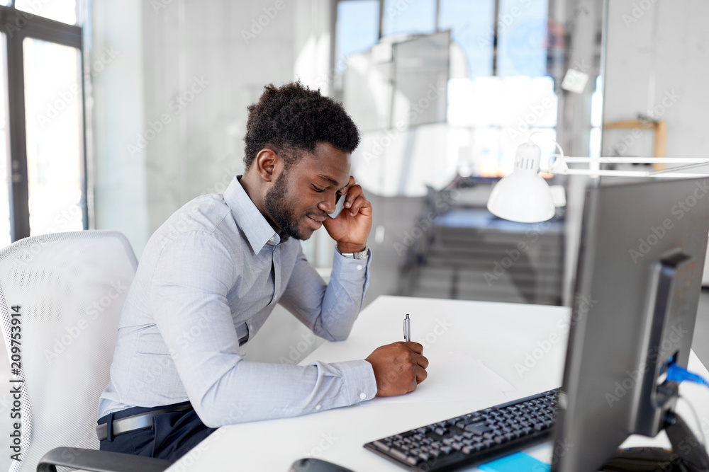 business, people, communication and technology concept - smiling african american businessman with papers and computer calling on smartphone at office