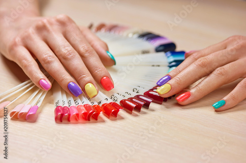 Female manicured hands, nails samples. Female hands with beautiful summer manicure on salon table with nails colors palette. Women nails treatment and care. photo
