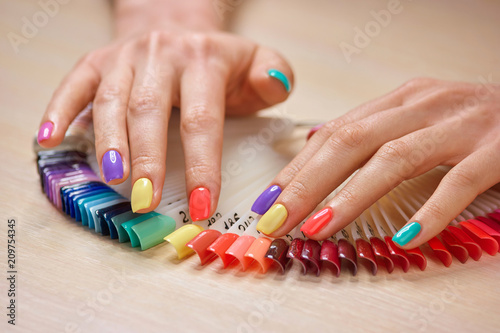 Summer colorful manicure on female hands. Beautiful caucasian lady hands with stylish summer manicure. Professional nails studio.