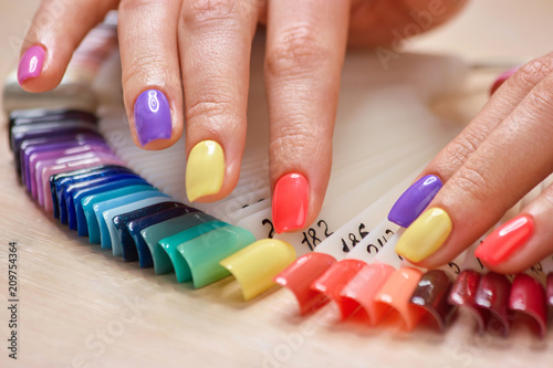 Summer colored manicure on female fingers. Womans hands with pastel colors nails  nails samples collection. Studio of art nails design.