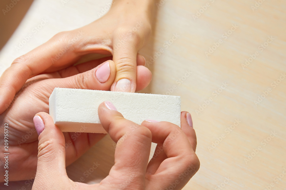 Beautician polishing nails to client. The process of buffing nails by manicurist. Beautiful female hands having spa manicure at beauty salon. Beautician polishing nails to client. The process of buffing nails by manicurist. Beautiful female hands having spa manicure at beauty salon.