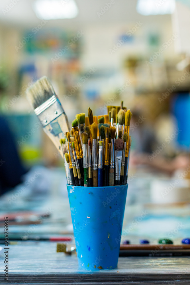 Paint brushes and crafting supplies on the table in a workshop.