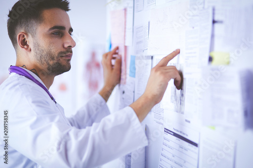 Young and confident male doctor portrait standing in medical office photo