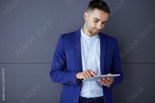 Happy young man using digital tablet isolated on grey background photo