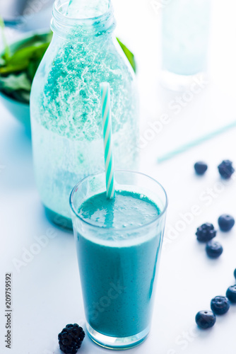 Blue Majik smooothie on tall glass with colored straw, over a blue colored wooden board against a clear background photo