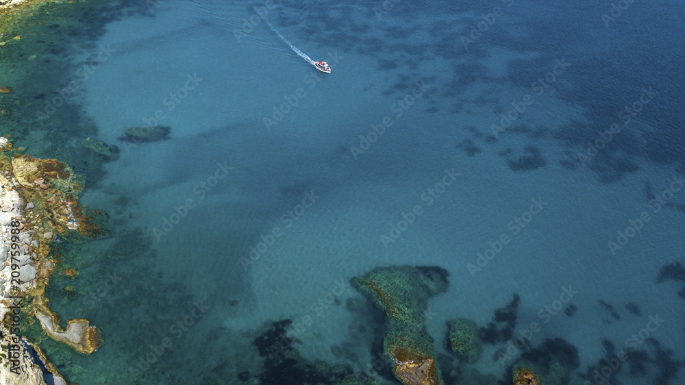 Aerial view of a white motorboat running on the azure waters of the Tyrrhenian Sea. On his trip near the coast the boat leaves a white trail in the waves ofeaves a white trail in the waves of the sea.
