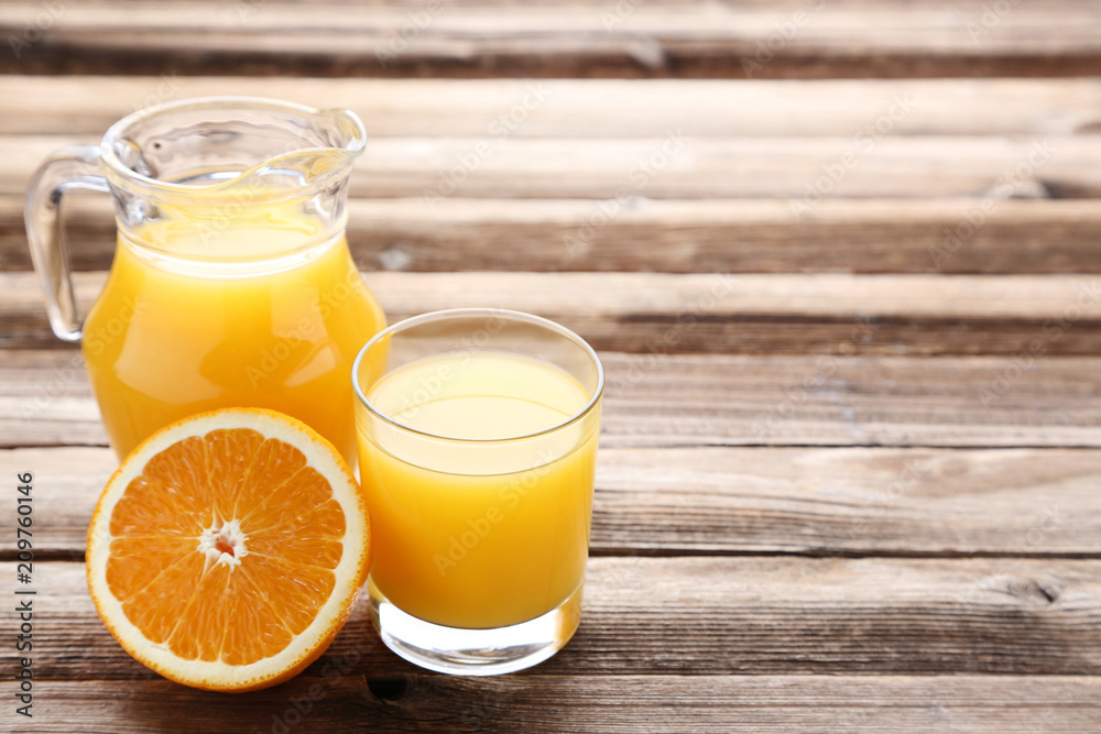 Orange fruit with jug and glass of juice on brown wooden table Orange fruit with jug and glass of juice on brown wooden table