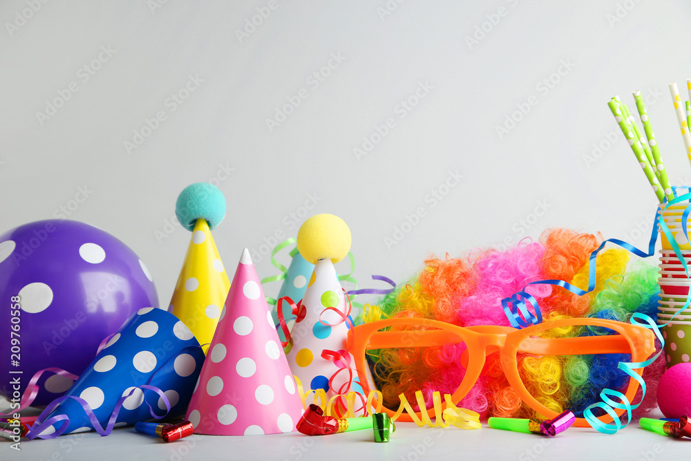 Birthday party caps, blowers and balloons on grey background