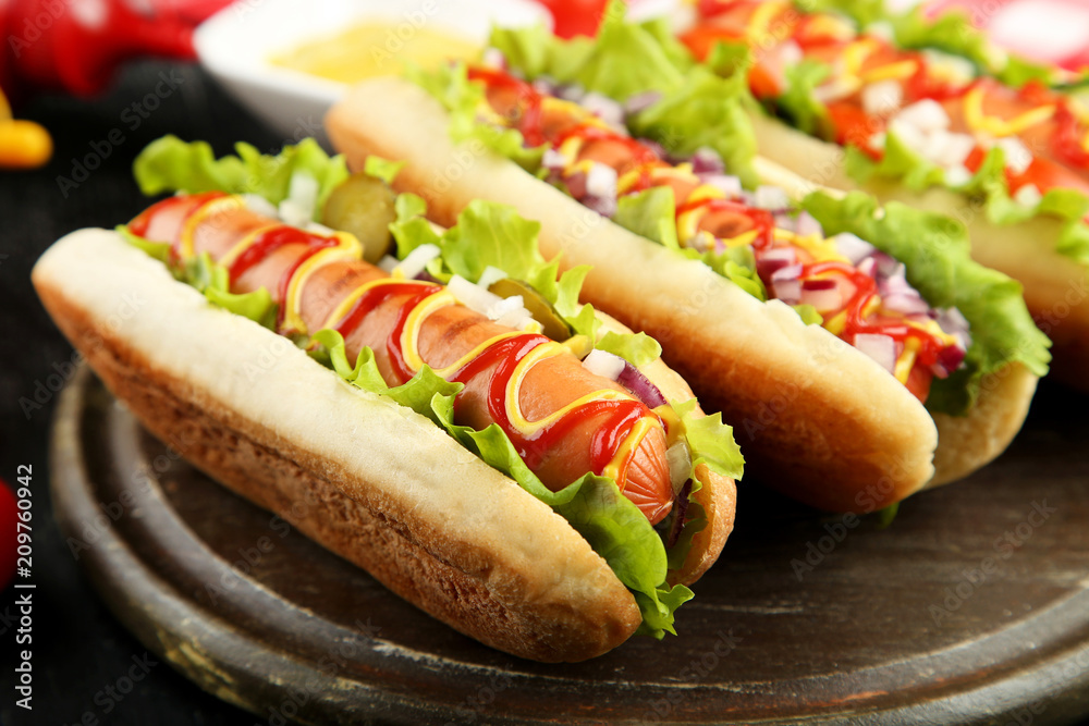Hot dogs with ketchup, mustard and vegetables on wooden table Hot dogs with ketchup, mustard and vegetables on wooden table