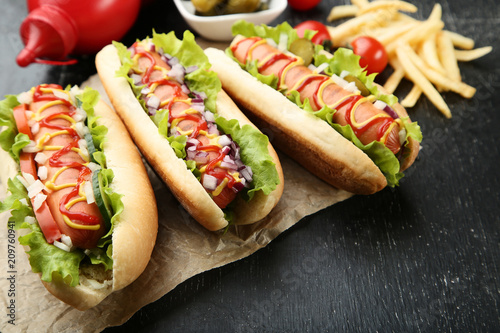 Hot dogs with ketchup, mustard and vegetables on wooden table