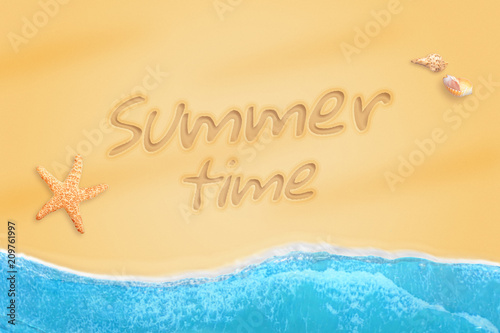 Summer time written on beach sand. Starfish and shells beside. Waves of the ocean clatter to the coast.
