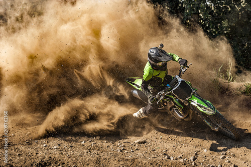 Photo Motocross rider creates a large cloud of dust and debris