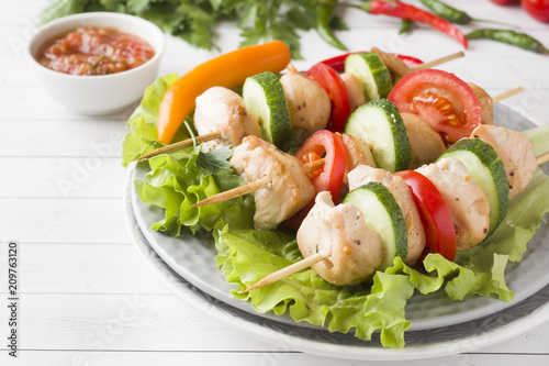 Traditional Turkey chicken kebab meat with tomatoes, cucumber and fresh herbs on a plate.