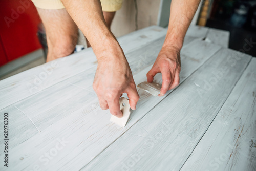 Putty in the hand of a person. Removing paint from the surface of the tree. Preparation of boards before impregnation with varnish. Application of putty.