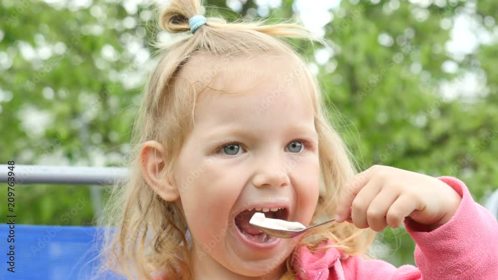 Cute little girl sits and eats ice cream. Child with ice cream. Funny little girl with ice cream. Kid eats ice cream and laughing Cute little girl sits and eats ice cream. Child with ice cream. Funny little girl with ice cream. Kid eats ice cream and laughing