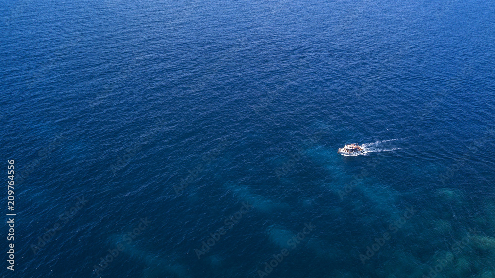 Aerial view of a small boat that runs on the blue waters of the Tyrrhenian Sea off the coast of Italy. The boat floats without problems on the calm and flat sea ..