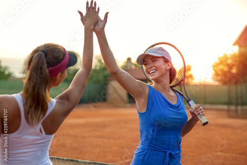Two beautiful young girls shaking hands after playing tennis