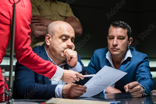 Portrait of a middle-aged man calling his attorney in order to ask for legal assistance, under the pressure of a difficult interrogation at the police