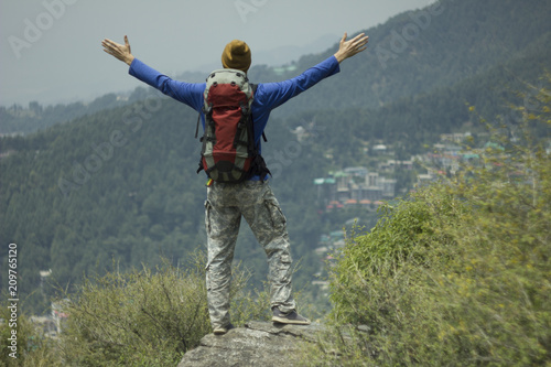 man tourist trekking with backpack in valley mountains success happy