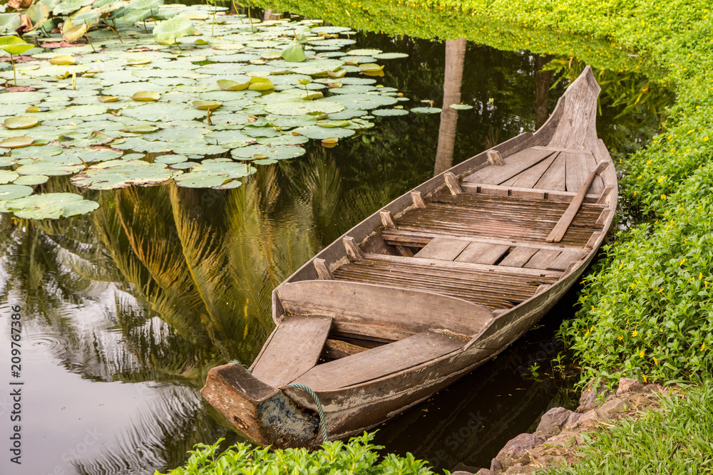 Small Wood Boat in a Lily Pond in Cambodia Small Wood Boat in a Lily Pond in Cambodia