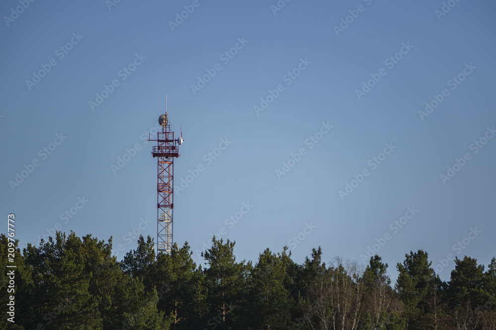 Radio tower in the forest around the blue sky