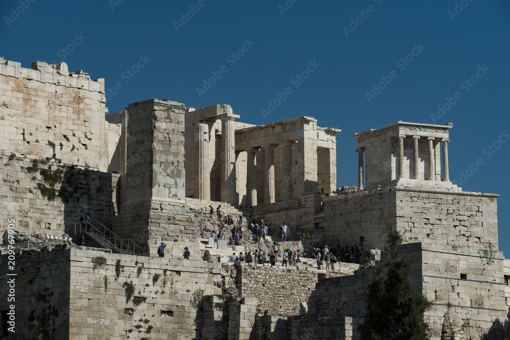 Tourists discover remains of ancient temple on hill. People on stone ruins on sunny blue sky. Travelling or vacation and wanderlust. Architecture and structure. Heritage and art