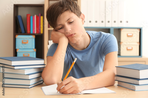 Tired teenager boy doing ho...