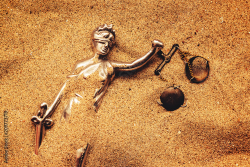 Statue of lady Justice buried in sand photo