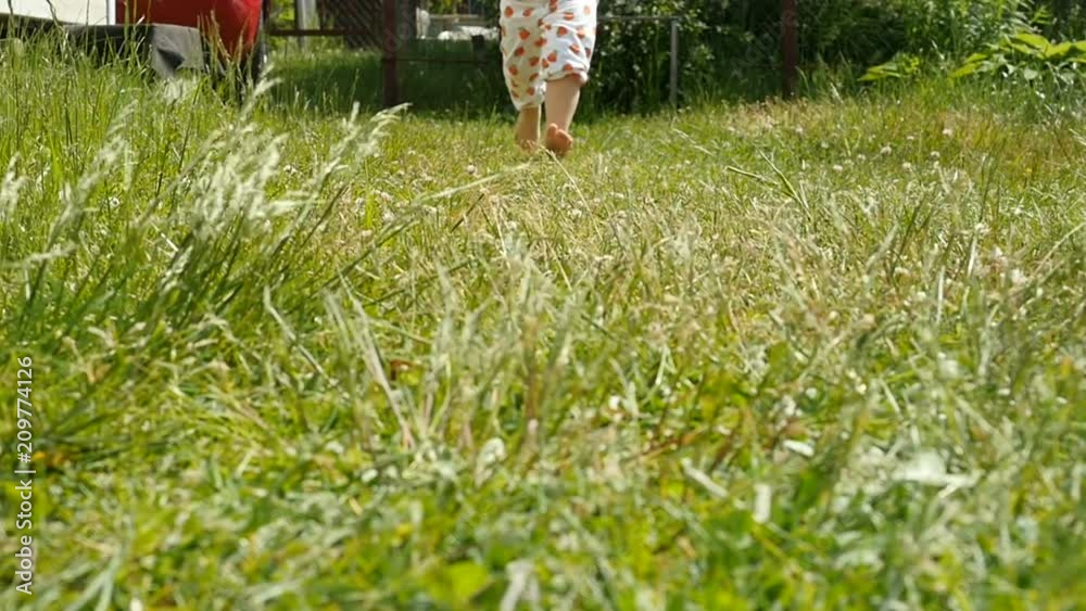 Vidéo Stock Little kid girl naked legs, barefoot walking on a ground, meadow. Baby feet on the grass. Slow motion | Adobe Stock