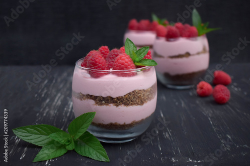 Sweet raspberry mousse in glass bowl on dark background