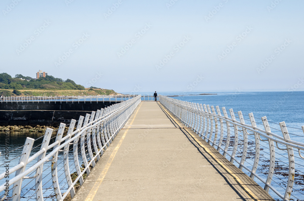 Lonely Person Walking on a Breakwater ona Clear Summer Day