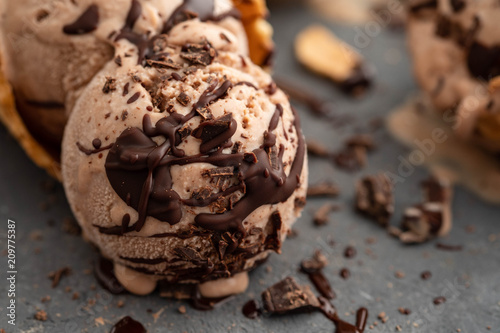 Homemade chocolate ice cream in waffle cones, with a spoon for ice cream, cocoa and pieces of dark chocolate. On a dark gray table. Copy space close view