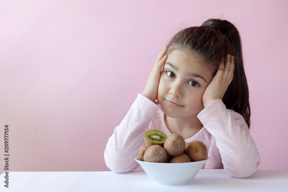 Cute little girl eating fresh kiwi fruits Cute little girl eating fresh kiwi fruits