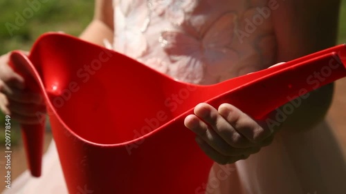 Red watering can in the hands of a little girl photo