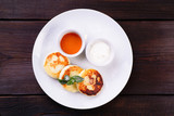 Cottage cheese pancakes with honey and sour cream, syrniki on white plate. Ukrainian or russian traditional cuisine, sweet and nutritional breakfast