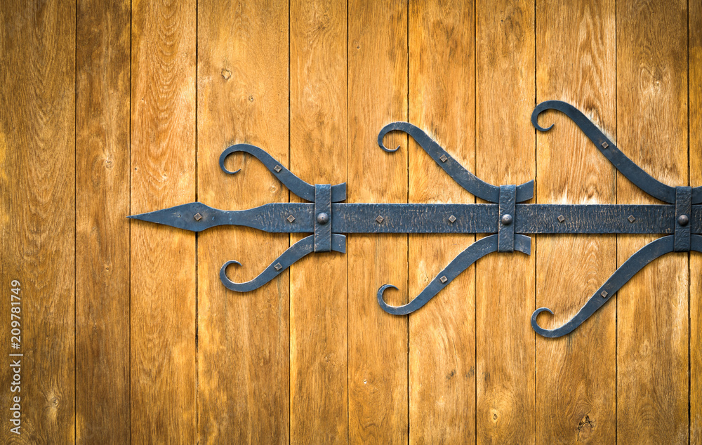 Forged elements on a brown wooden gate background Forged elements on a brown wooden gate background