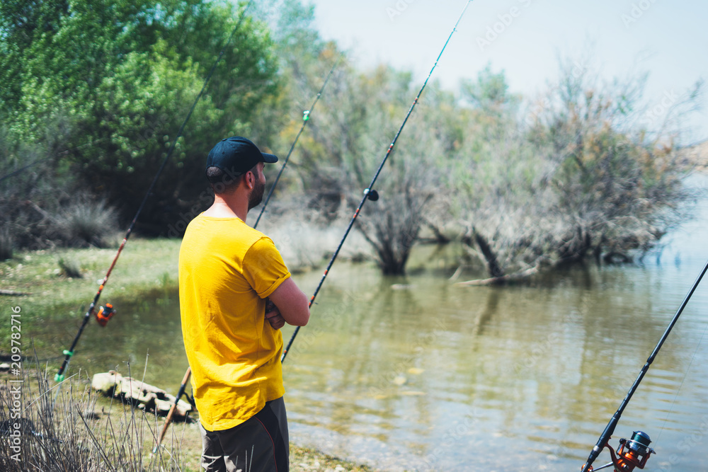 young man looking on seascape and holds a fishing rod and catches fish in the nature background, hipster fisherman spends vacation on the blue ocean, hobby fishing, rural outdoor sport tourism young man looking on seascape and holds a fishing rod and catches fish in the nature background, hipster fisherman spends vacation on the blue ocean, hobby fishing, rural outdoor sport tourism