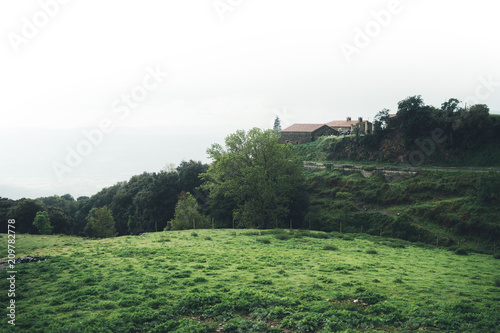 morning mist in the mountain peaks on natural landscape. Green valley on background foggy dramatic sky, house in horizon perspective view of scenery hills Northern Spain. Travel mockup concept