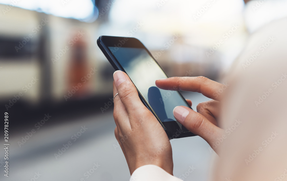 blogger hipster using in hands gadget mobile phone, woman texting message on blank screen smartphone, texting message, mockup online wifi internet concept, hipster waiting on station platform