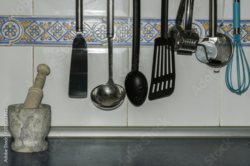 hung kitchenware and a stone mortar with a tile background
