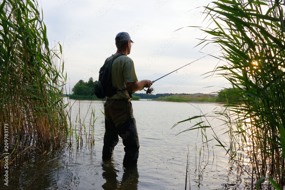 Fisherman standing in the lake and catching the fish Fisherman standing in the lake and catching the fish