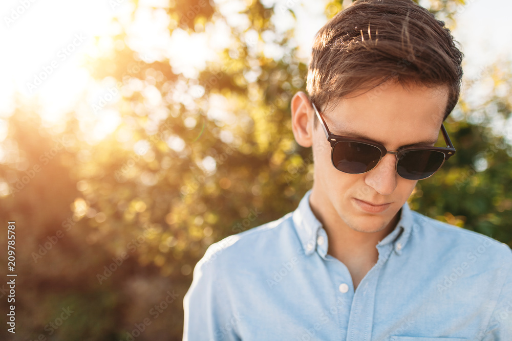 Beautiful stylish guy with glasses, posing on the beach, at sunset, hipster posing in stylish clothes, for advertising, text insertion Beautiful stylish guy with glasses, posing on the beach, at sunset, hipster posing in stylish clothes, for advertising, text insertion