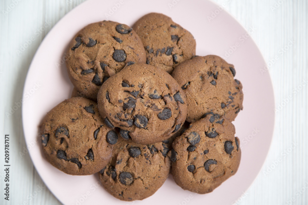 Delicious chocolate cookies on a pink plate on a white wooden table, top view. From above. Closeup. Delicious chocolate cookies on a pink plate on a white wooden table, top view. From above. Closeup.