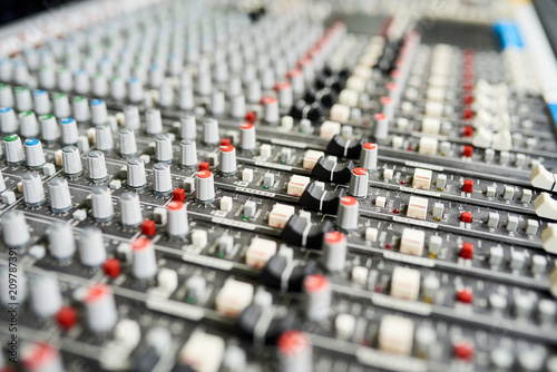 Close-up shot of colorful knobs on music mixer control panel in sound studio. 